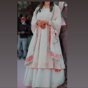 White and silver hand embroidered lengha with red accents on chunni.